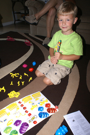 Trey plays his new Cootie game while eating a swirl lollipop